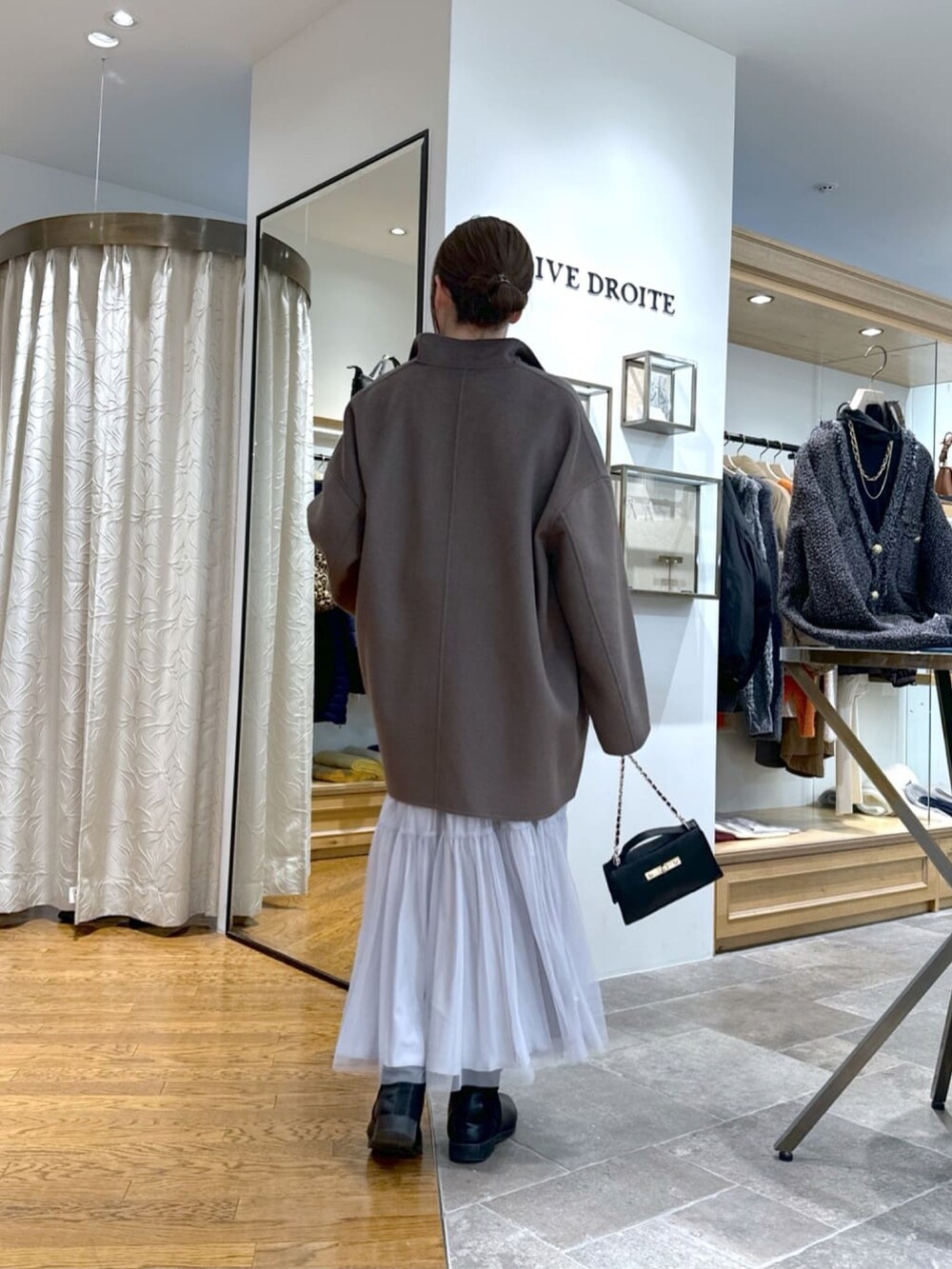 ブラウン系のその他アウター、ブラック系のハンドバッグ、グレー系のスカートを着用したレディースの冬コーディネートの4枚目の写真