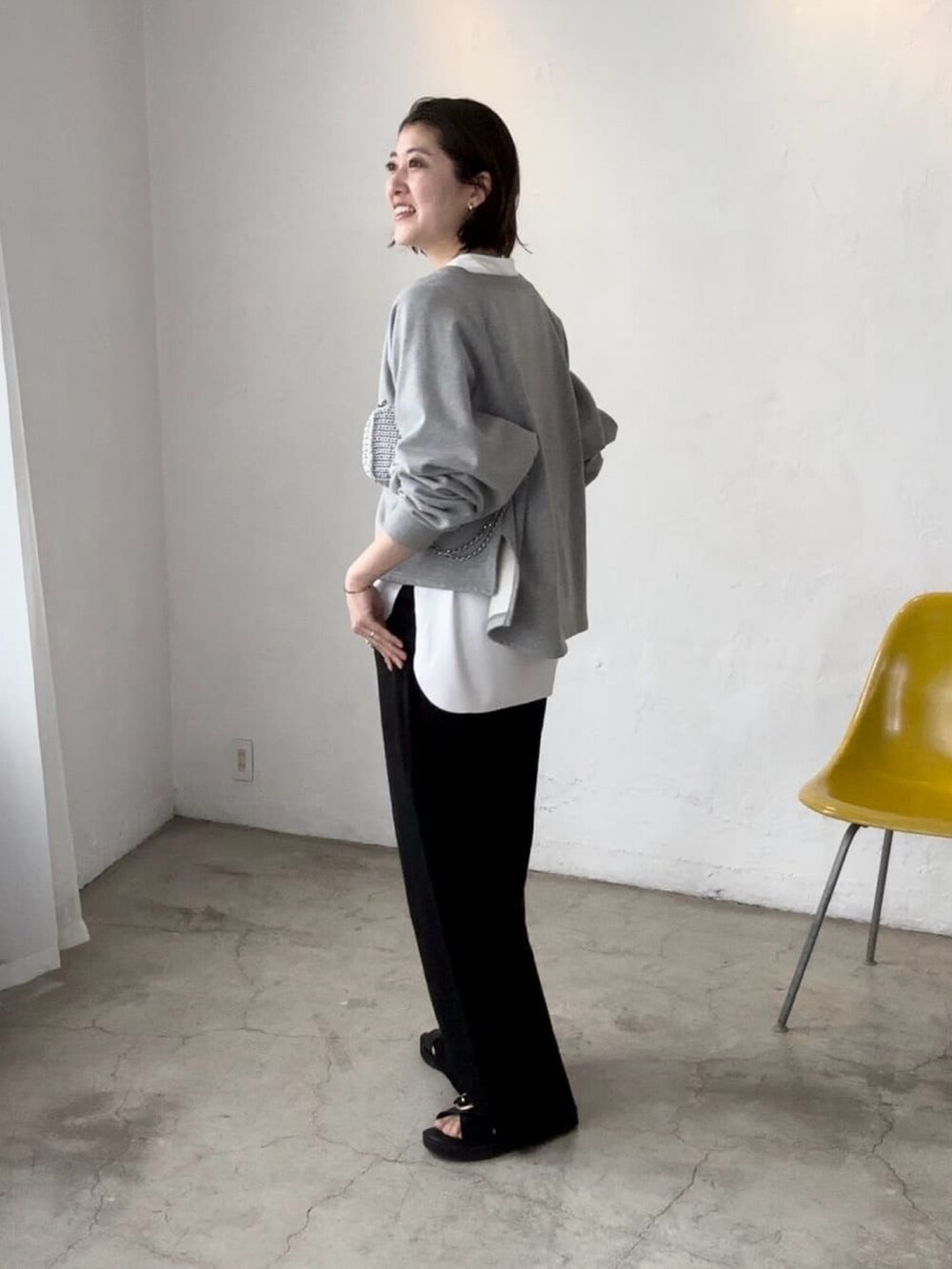 グレー系のスウェット、ブラック系のスラックス、ブラック系のサンダルを着用したレディースの秋コーディネートの2枚目の写真