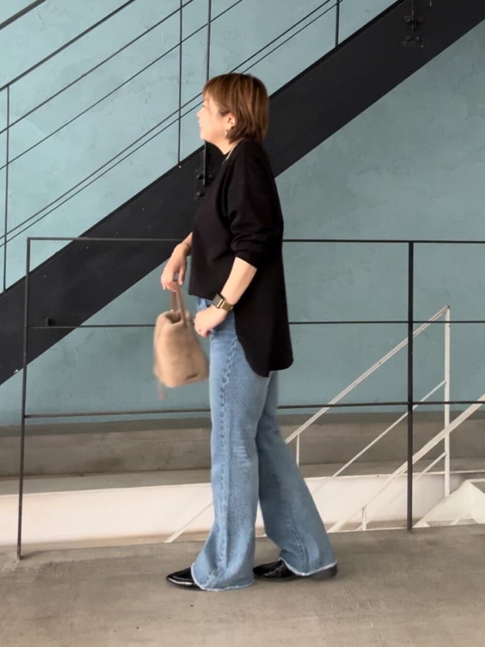 ホワイト系のTシャツ/カットソー、ブルー系のデニムパンツ、ベージュ系のハンドバッグを着用したレディースの秋コーディネートの3枚目の写真