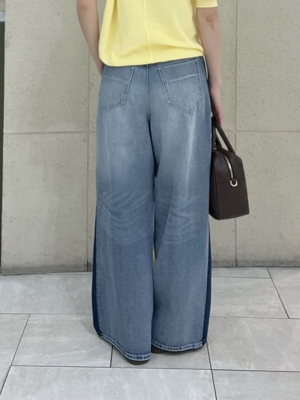 ブラウン系のボストンバッグ、イエロー系のニット/セーター、ブルー系のデニムパンツを着用したレディースの春コーディネートの9枚目の写真