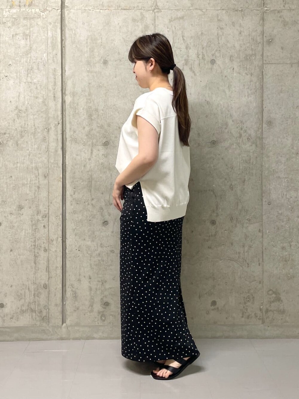 ホワイト系のニット/セーター、ブラック系のスカート、イエロー系のハンドバッグを着用したレディースの夏コーディネートの2枚目の写真