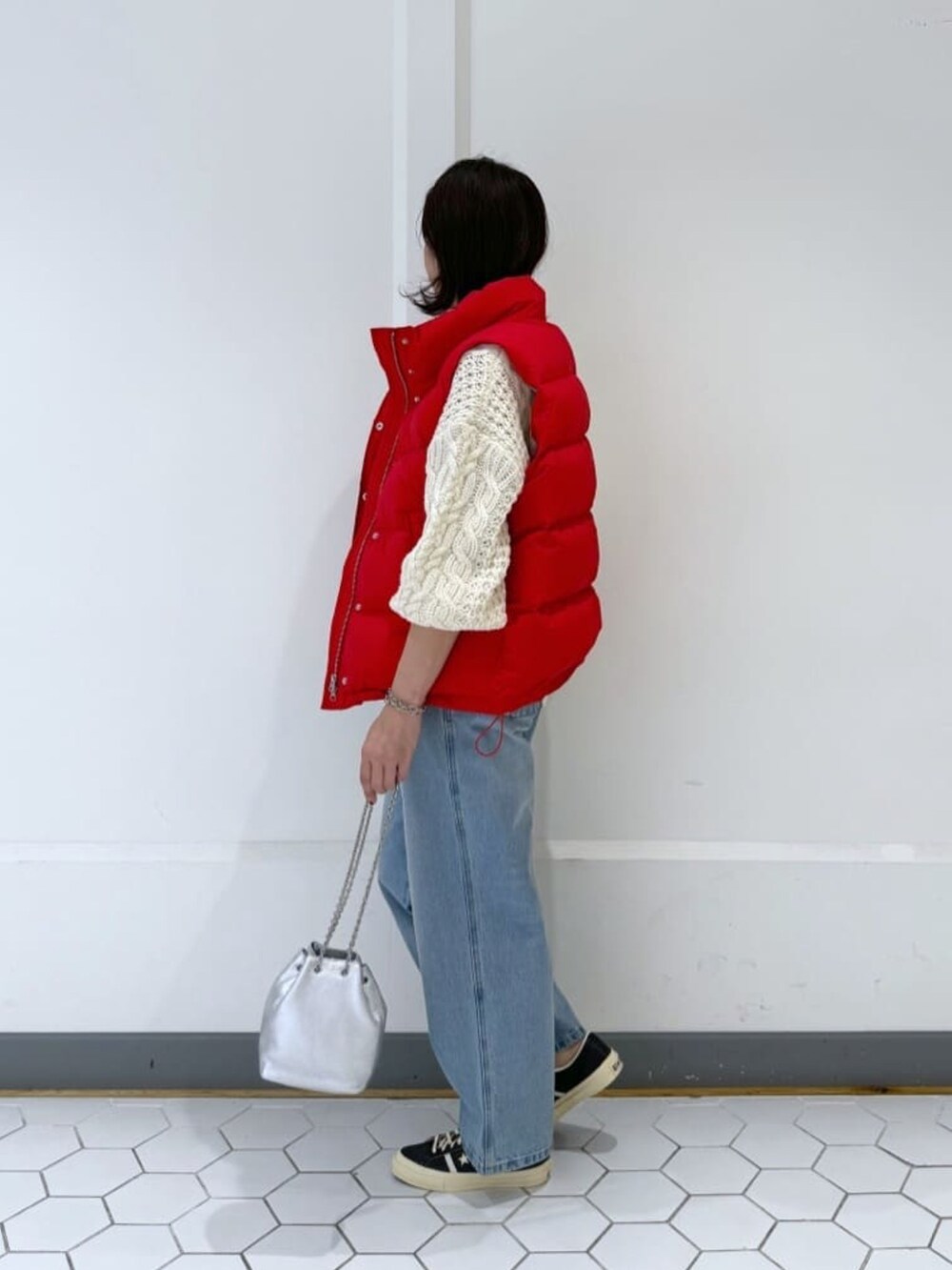 レッド系のダウンベスト、ブルー系のデニムパンツ、ホワイト系のニット/セーターを着用したレディースの冬コーディネートの3枚目の写真