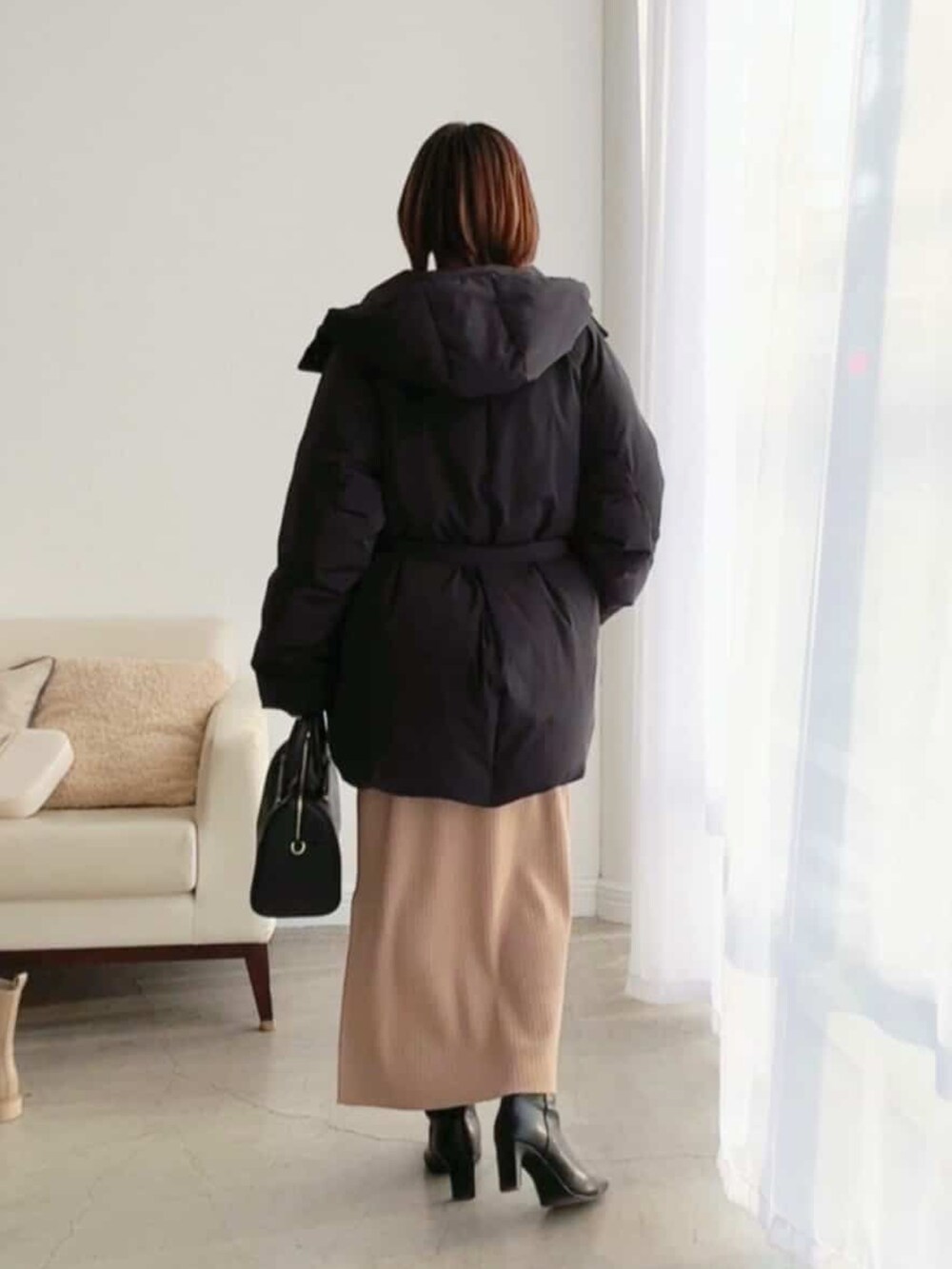 ブラック系のダウンジャケット/コート、ブラウン系のワンピース、ブラック系のブーツを着用したレディースの冬コーディネートの3枚目の写真