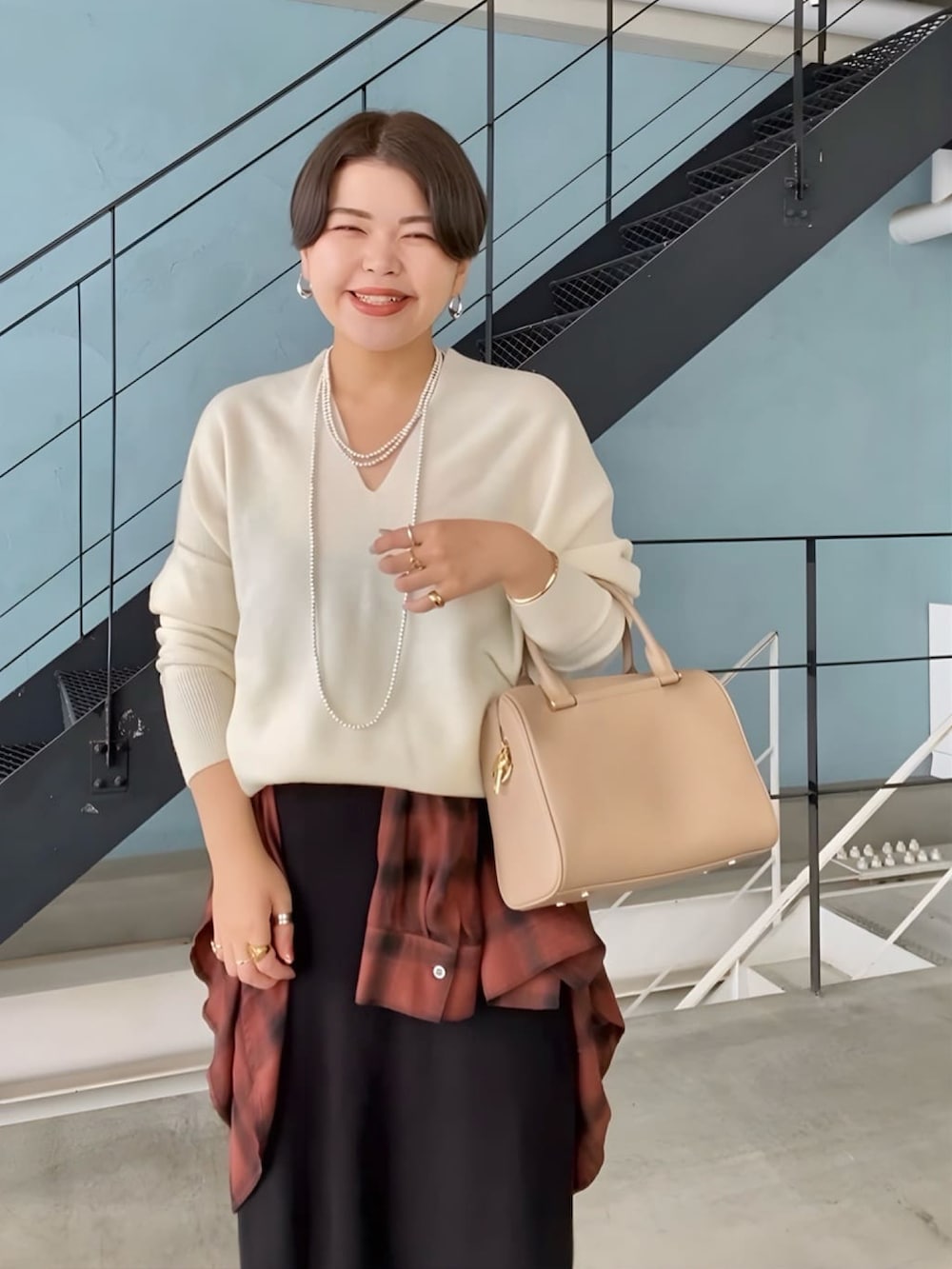 ホワイト系のニット/セーター、ベージュ系のボストンバッグ、ブラック系のスカートを着用したレディースの冬コーディネートの3枚目の写真