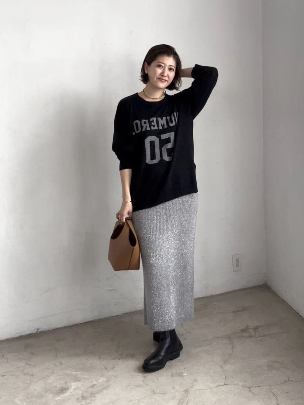 ブラック系のニット/セーター、グレー系のスカート、ブラック系のブーツを着用したレディースの秋コーディネートの2枚目の写真