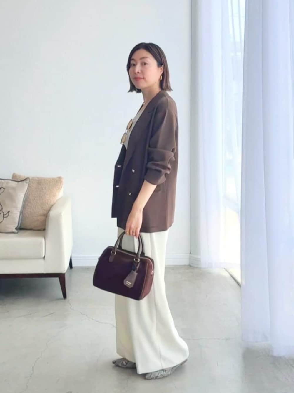 ホワイト系のスラックス、グレー系のパンプス、ホワイト系のキャミソールを着用したレディースの夏コーディネートの2枚目の写真