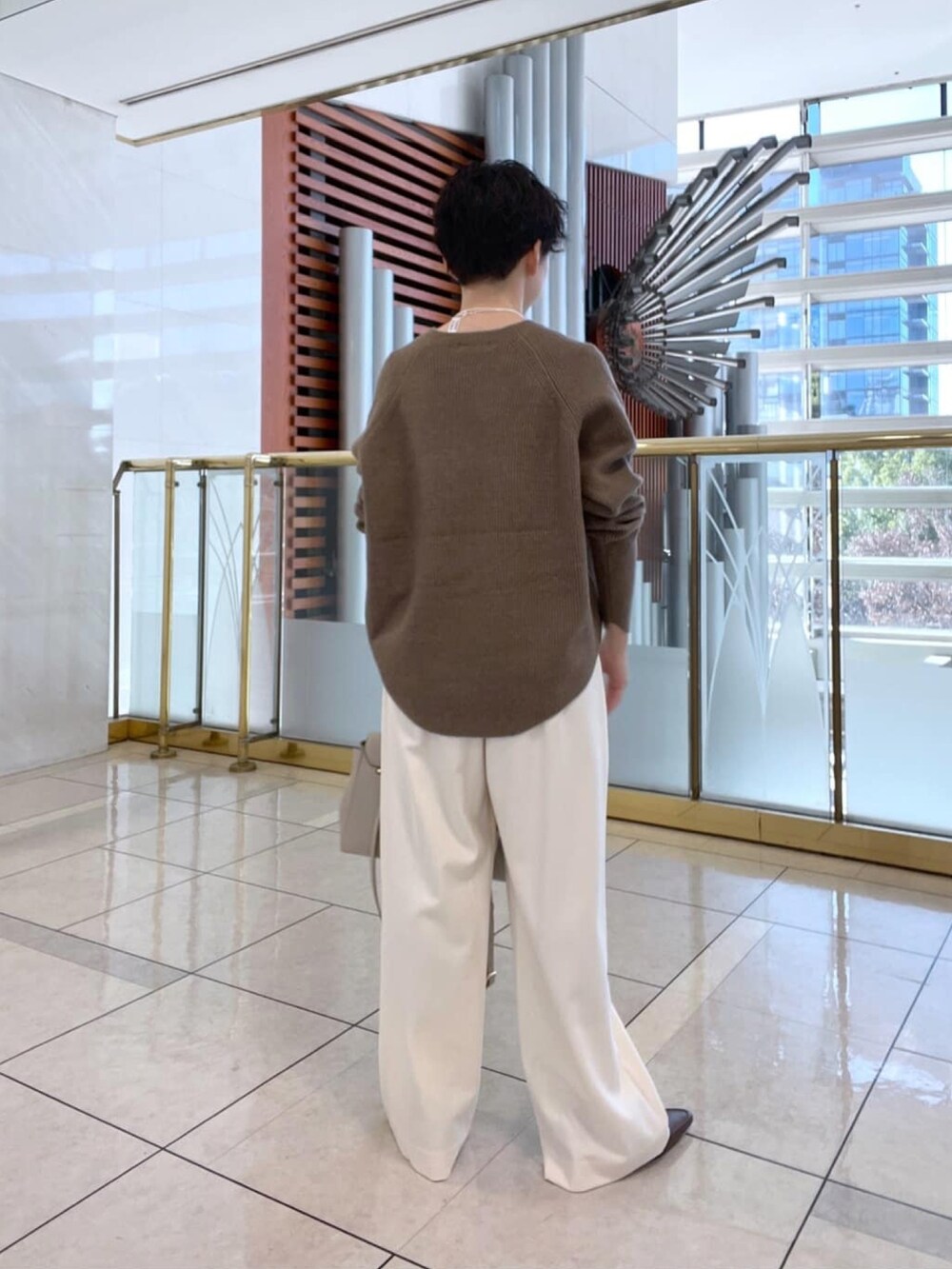 イエロー系のニット/セーター、ホワイト系のその他パンツ、ブラウン系のローファーを着用したレディースの冬コーディネートの3枚目の写真