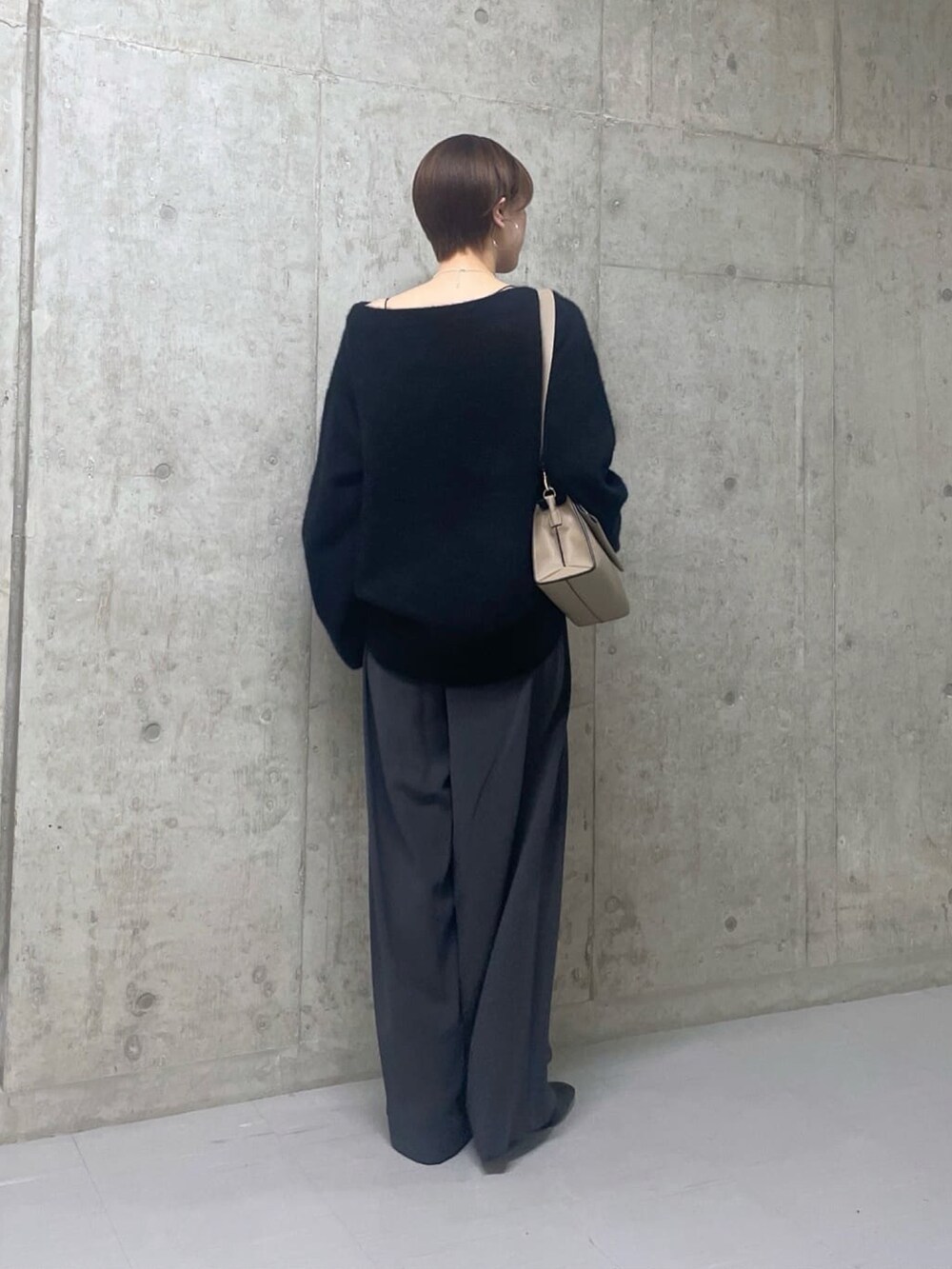 ベージュ系のショルダーバッグ、ブラック系のニット/セーター、グレー系のスラックスを着用したレディースの秋コーディネートの2枚目の写真