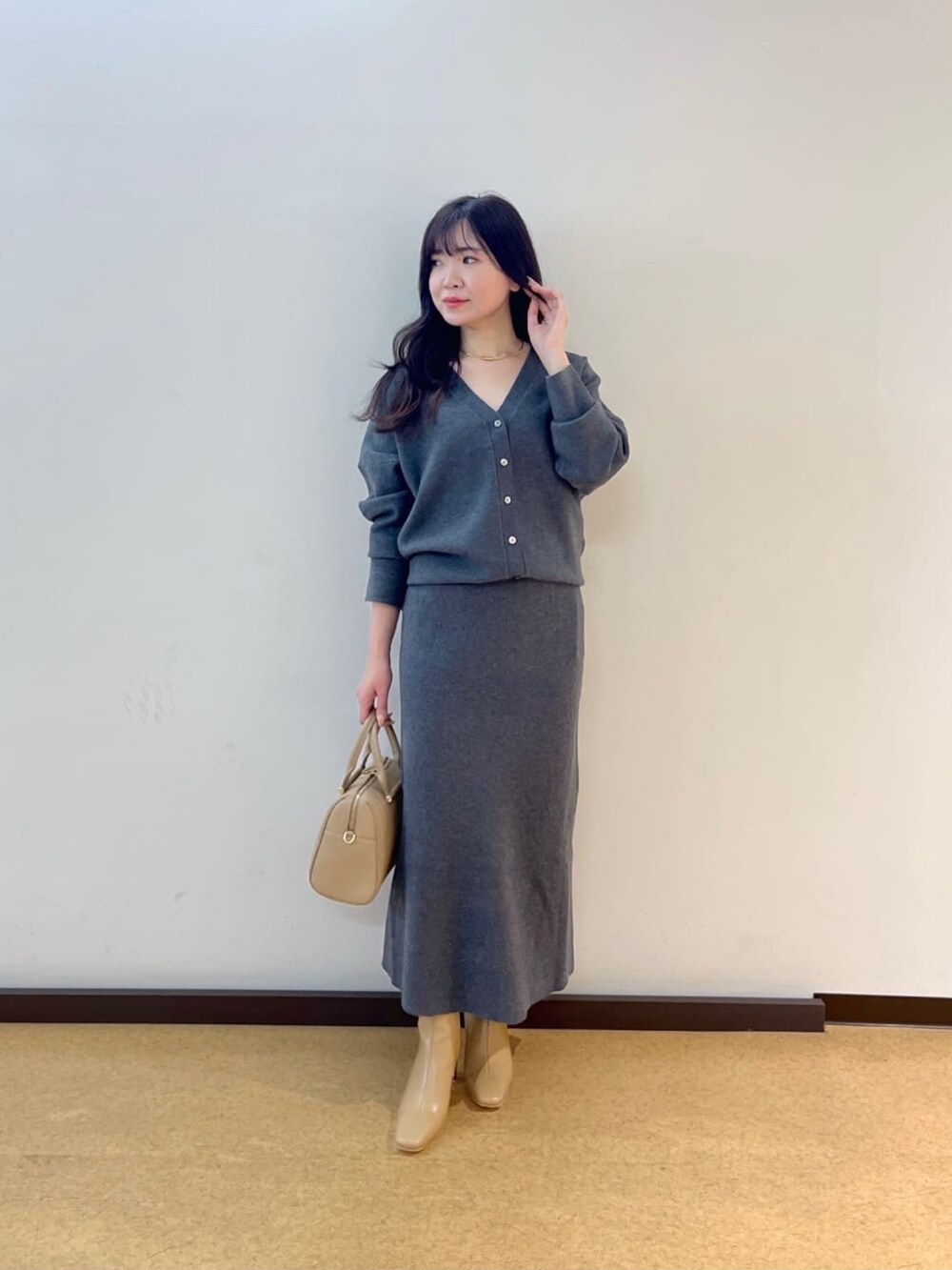 グレー系のカーディガン/ボレロ、グレー系のスカート、ベージュ系のブーツを着用したレディースの秋コーディネートの2枚目の写真