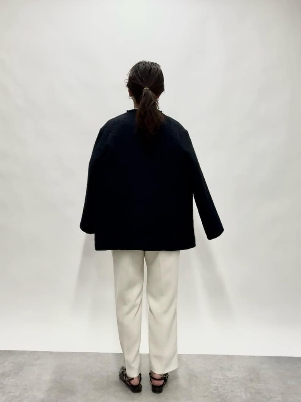 ブルー系のノーカラージャケット、ブラック系のショルダーバッグ、ホワイト系のその他パンツを着用したレディースの冬コーディネートの3枚目の写真