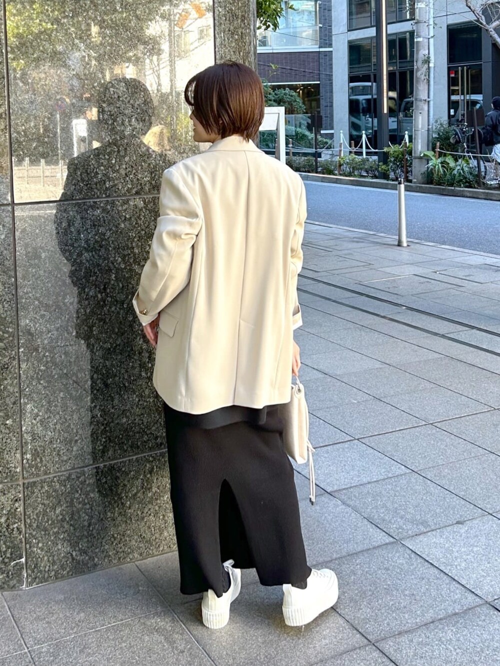 ブラック系のTシャツ/カットソー、ベージュ系のテーラードジャケット、ブラック系のスカートを着用したレディースの春コーディネートの3枚目の写真