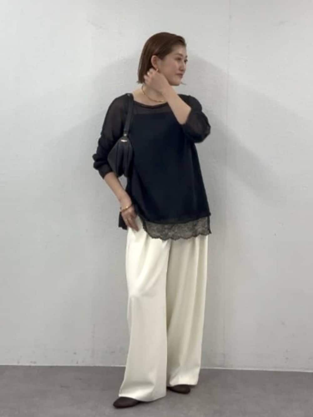 ホワイト系のスラックス、ブラック系のニット/セーター、ブラック系のキャミソールを着用したレディースの春コーディネートの2枚目の写真