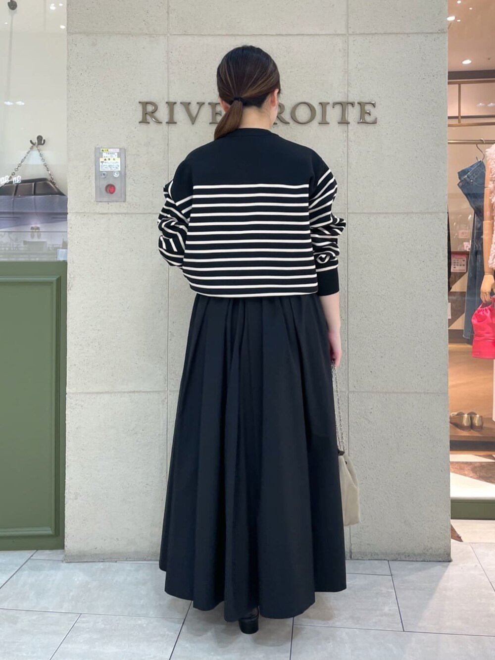 ブラック系のニット/セーター、ブラック系のスカート、ブラック系のローファーを着用したレディースの秋コーディネートの4枚目の写真