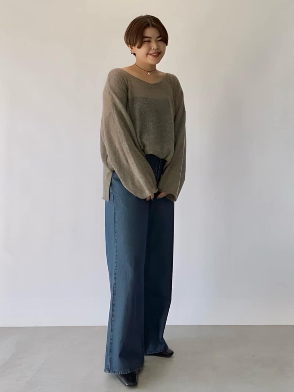 ブラウン系のニット/セーター、ブルー系のデニムパンツ、ブラック系のネックレスを着用したレディースの秋コーディネートの2枚目の写真