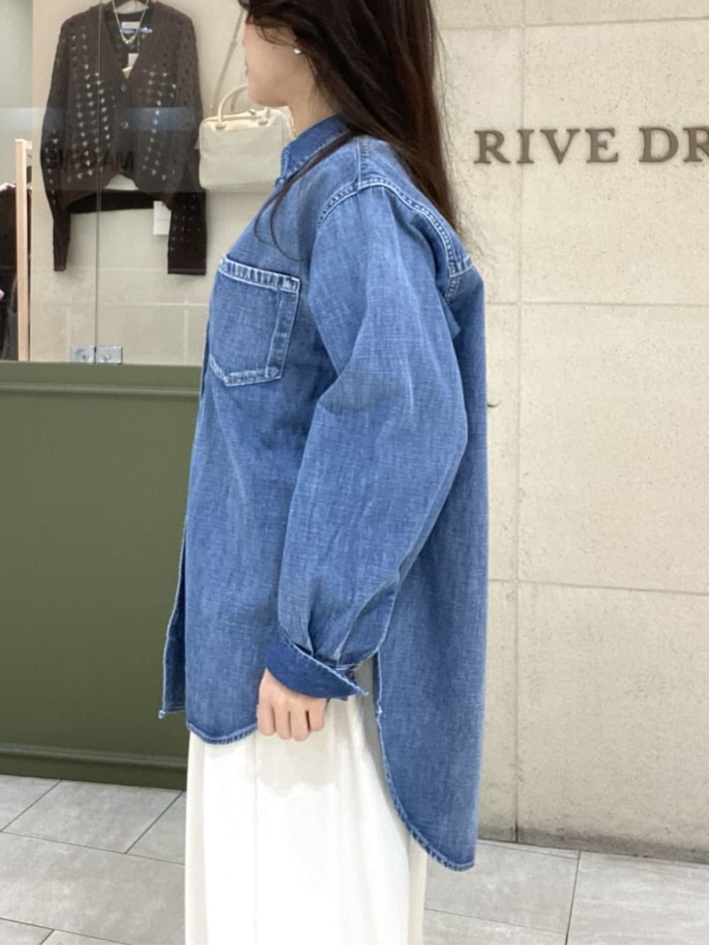 ホワイト系のスラックス、ブルー系のシャツ/ブラウス、ブラウン系のボストンバッグを着用したレディースの春コーディネートの5枚目の写真