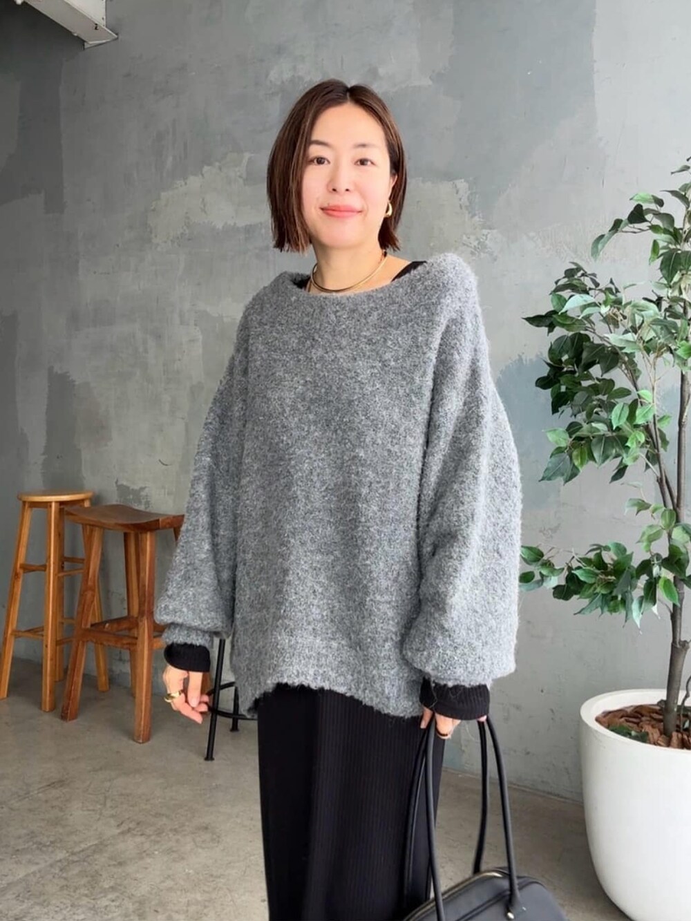 グレー系のニット/セーター、ブラック系のワンピース、ブラック系のショルダーバッグを着用したレディースの秋コーディネートの4枚目の写真