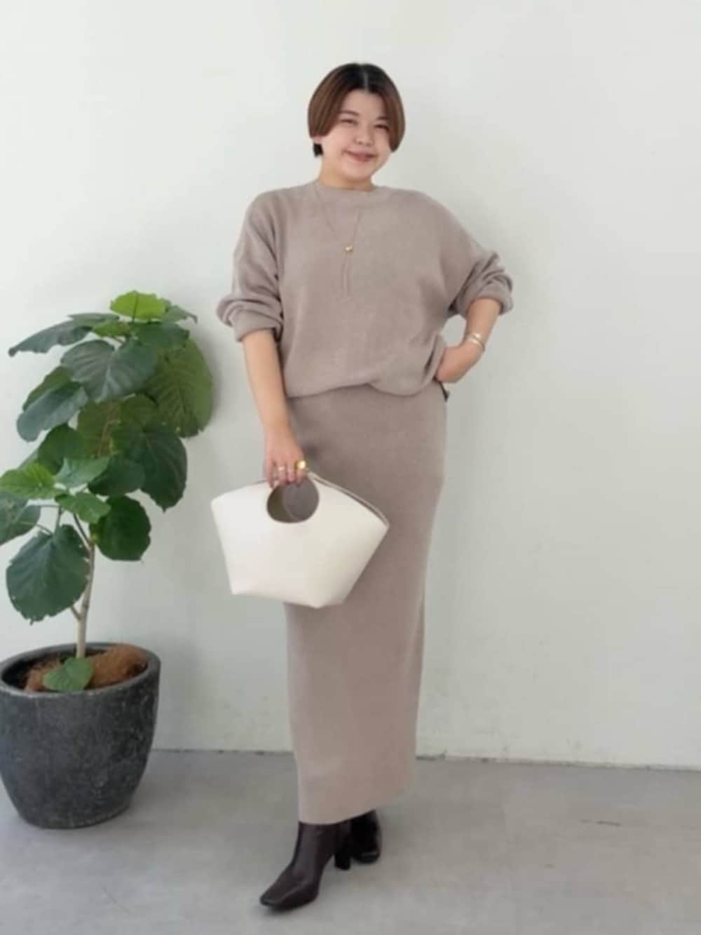 ホワイト系のハンドバッグ、ホワイト系のパーカー、ブラウン系のニット/セーターを着用したレディースの冬コーディネートの4枚目の写真