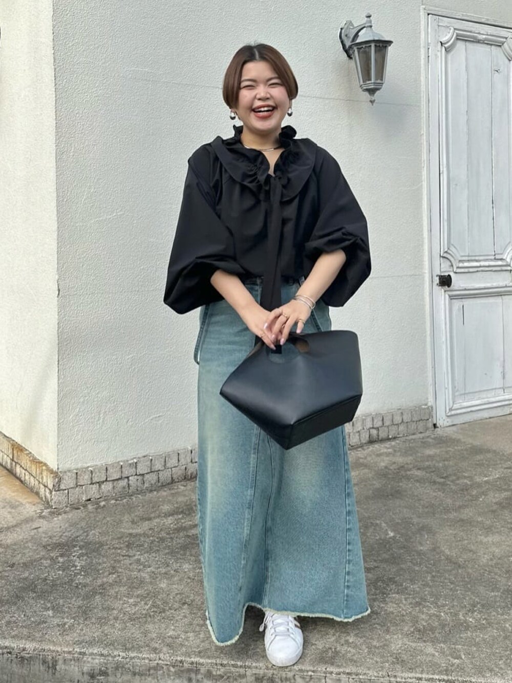 ブラック系のシャツ/ブラウス、ブラック系のハンドバッグ、ブルー系のデニムスカートを着用したレディースの冬コーディネートの2枚目の写真