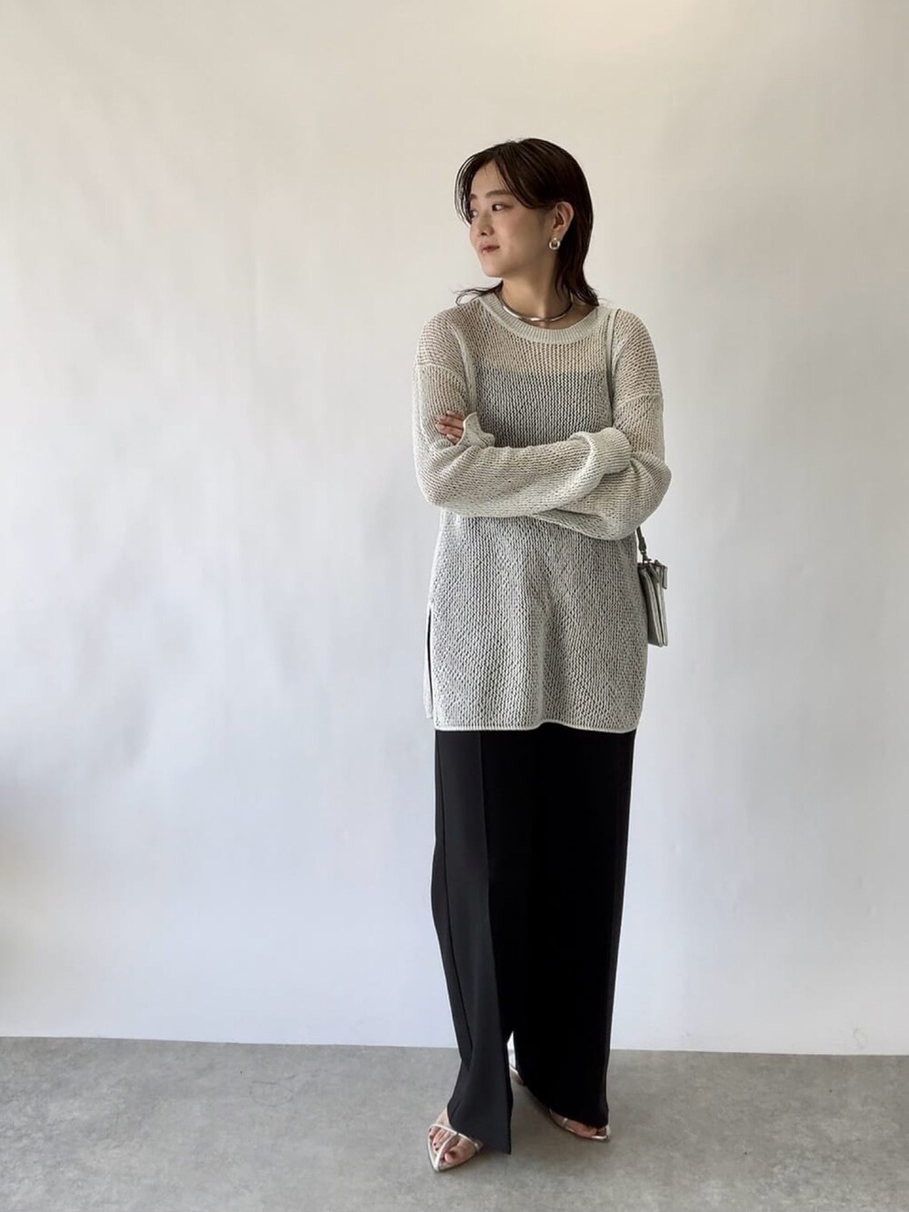 ブルー系のニット/セーター、グレー系のスラックスを着用したレディースの春コーディネートの2枚目の写真