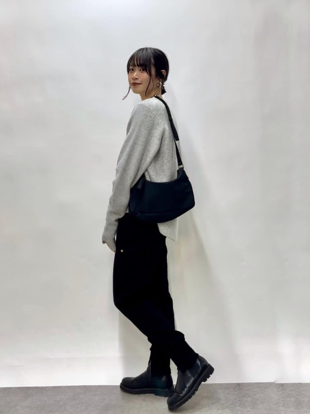 ブラック系のスウェットパンツ、ブラック系のブーツ、グレー系のニット/セーターを着用したレディースの冬コーディネートの4枚目の写真