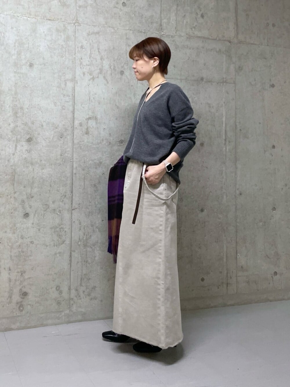 グレー系のニット/セーター、グレー系のデニムスカート、ブラック系のショルダーバッグを着用したレディースの冬コーディネートの2枚目の写真
