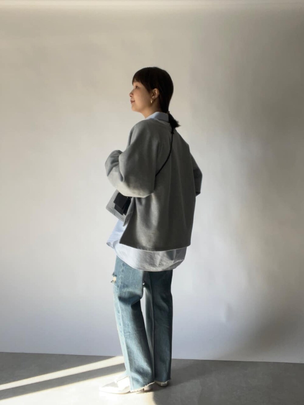 ブラック系のショルダーバッグ、ブルー系のシャツ/ブラウス、ブルー系のデニムパンツを着用したレディースの冬コーディネートの2枚目の写真