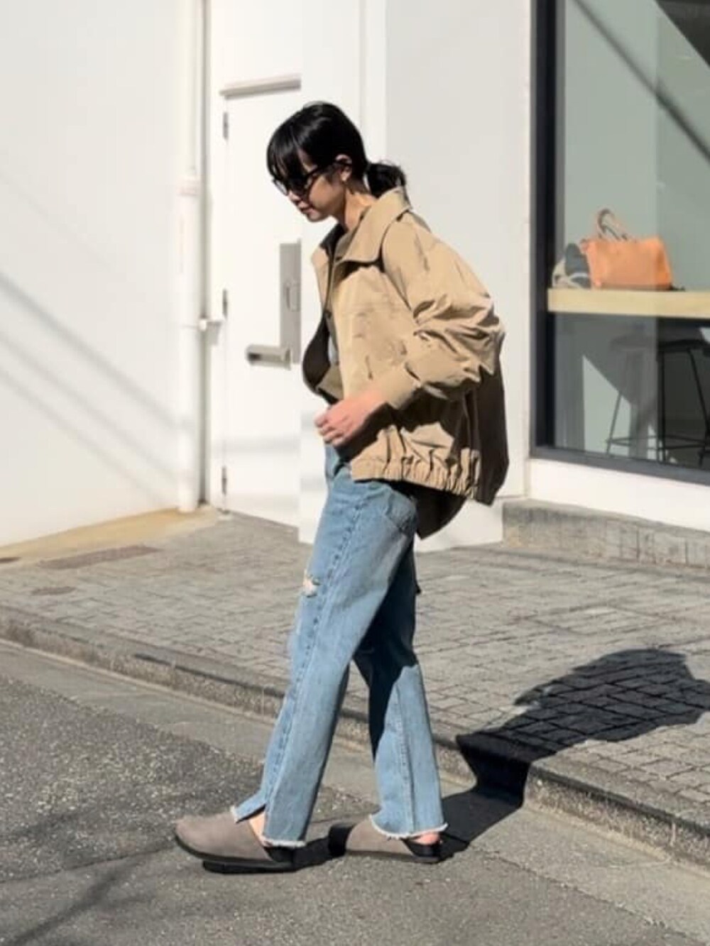 グリーン系のシャツ/ブラウス、ベージュ系のブルゾン、ブルー系のデニムパンツを着用したレディースの春コーディネートの2枚目の写真