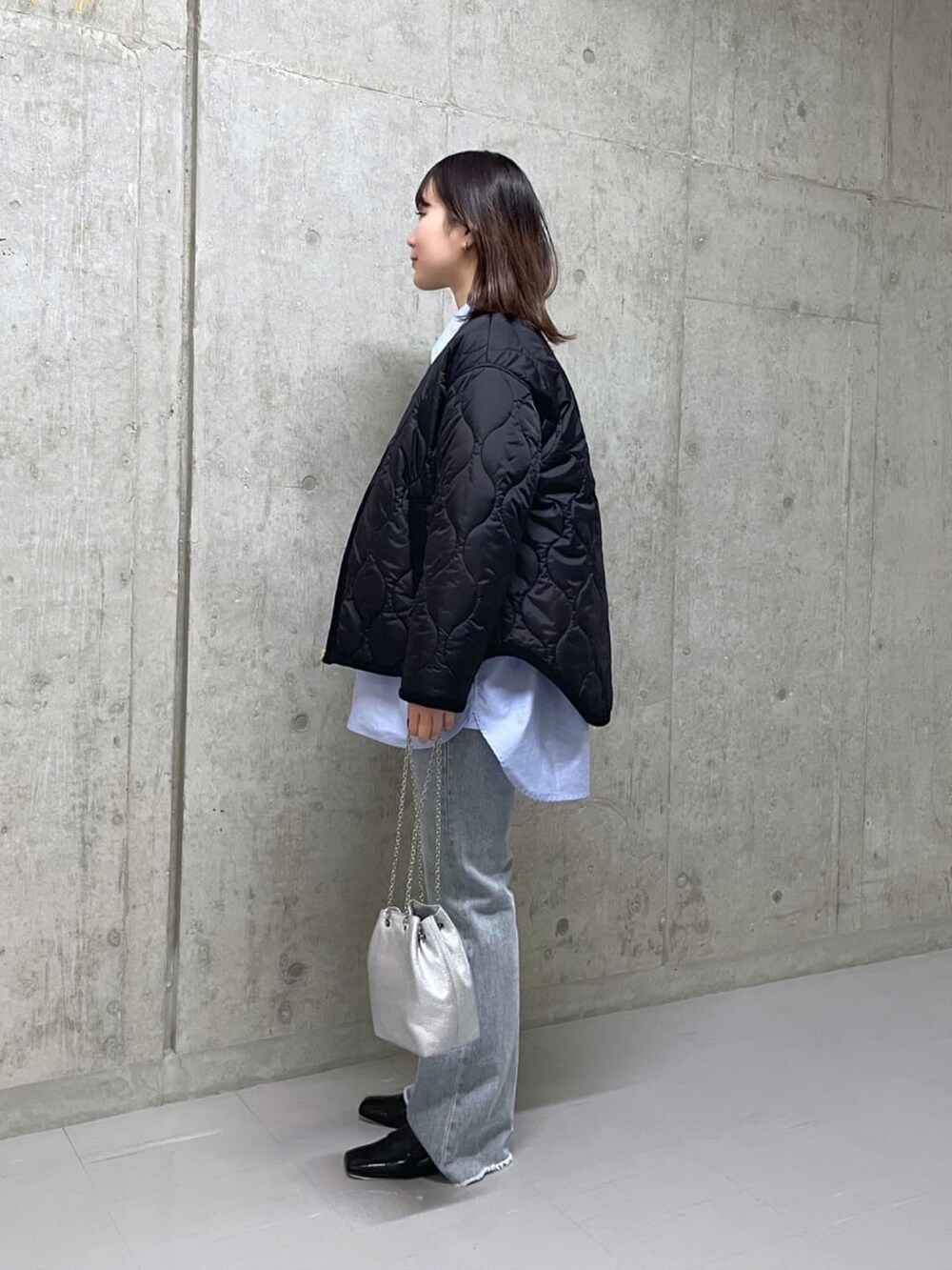 ブルー系のデニムパンツ、グレー系のニット/セーター、シルバー系のショルダーバッグを着用したレディースの秋コーディネートの2枚目の写真