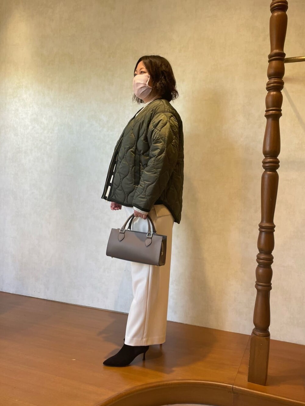 グリーン系のダウンジャケット/コート、ホワイト系のニット/セーター、ブラック系のブーツを着用したレディースの秋コーディネートの3枚目の写真