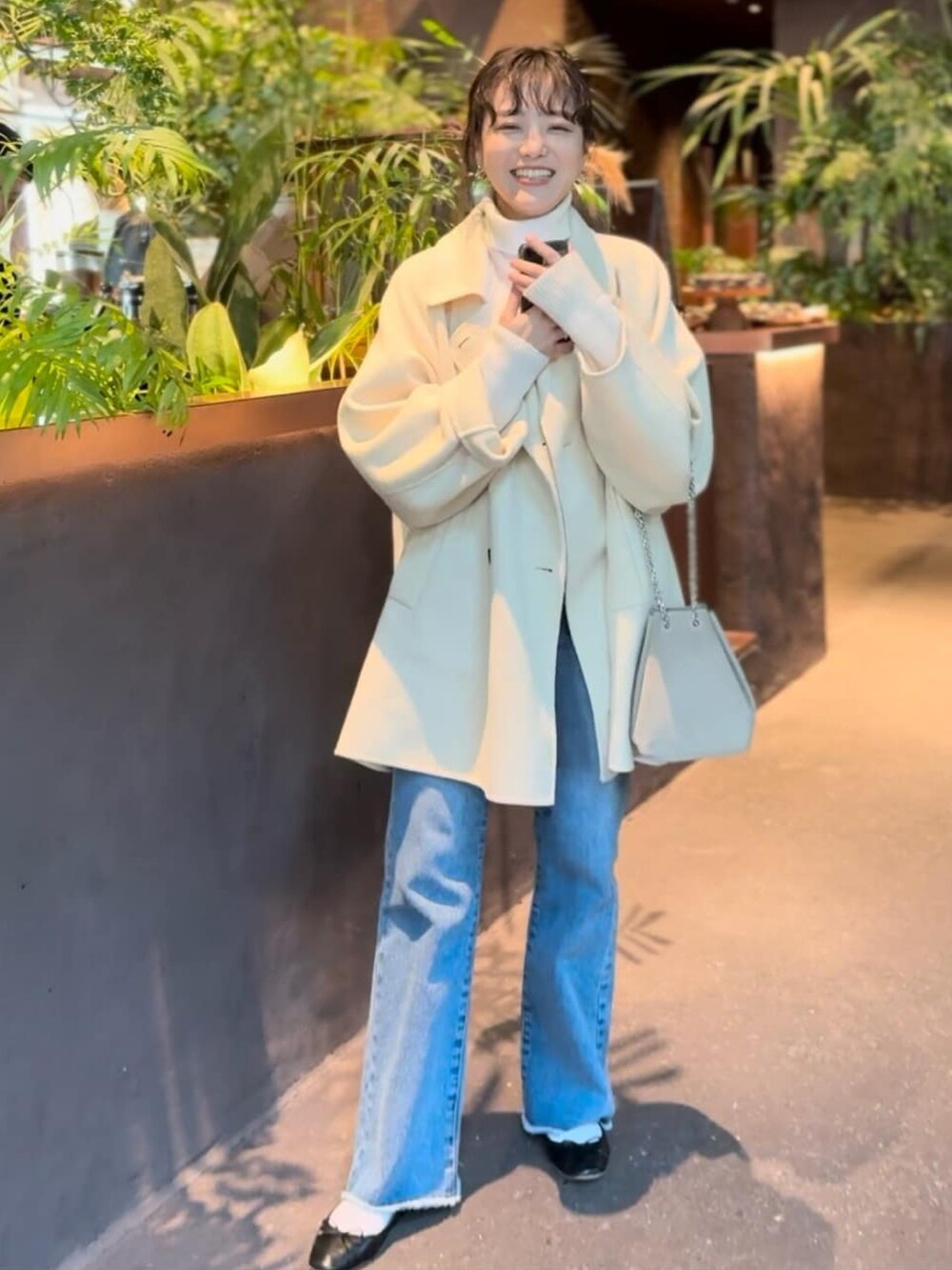 ベージュ系のその他アウター、ブルー系のデニムパンツ、ホワイト系のニット/セーターを着用したレディースの冬コーディネートの2枚目の写真