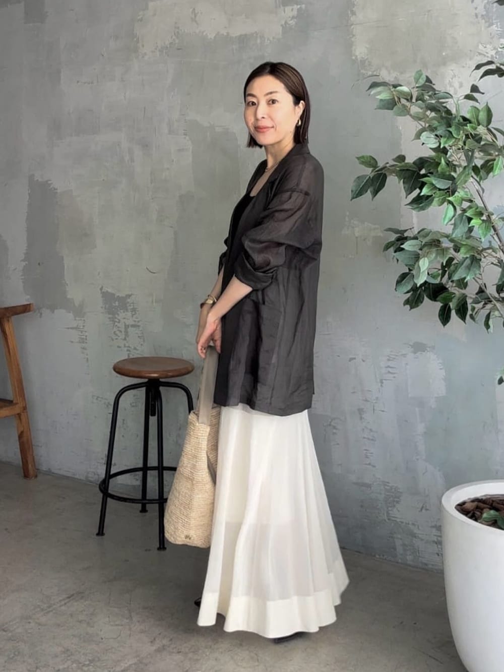 ブラック系のテーラードジャケット、ブラック系のキャミソール、ベージュ系のスカートを着用したレディースの夏コーディネートの2枚目の写真