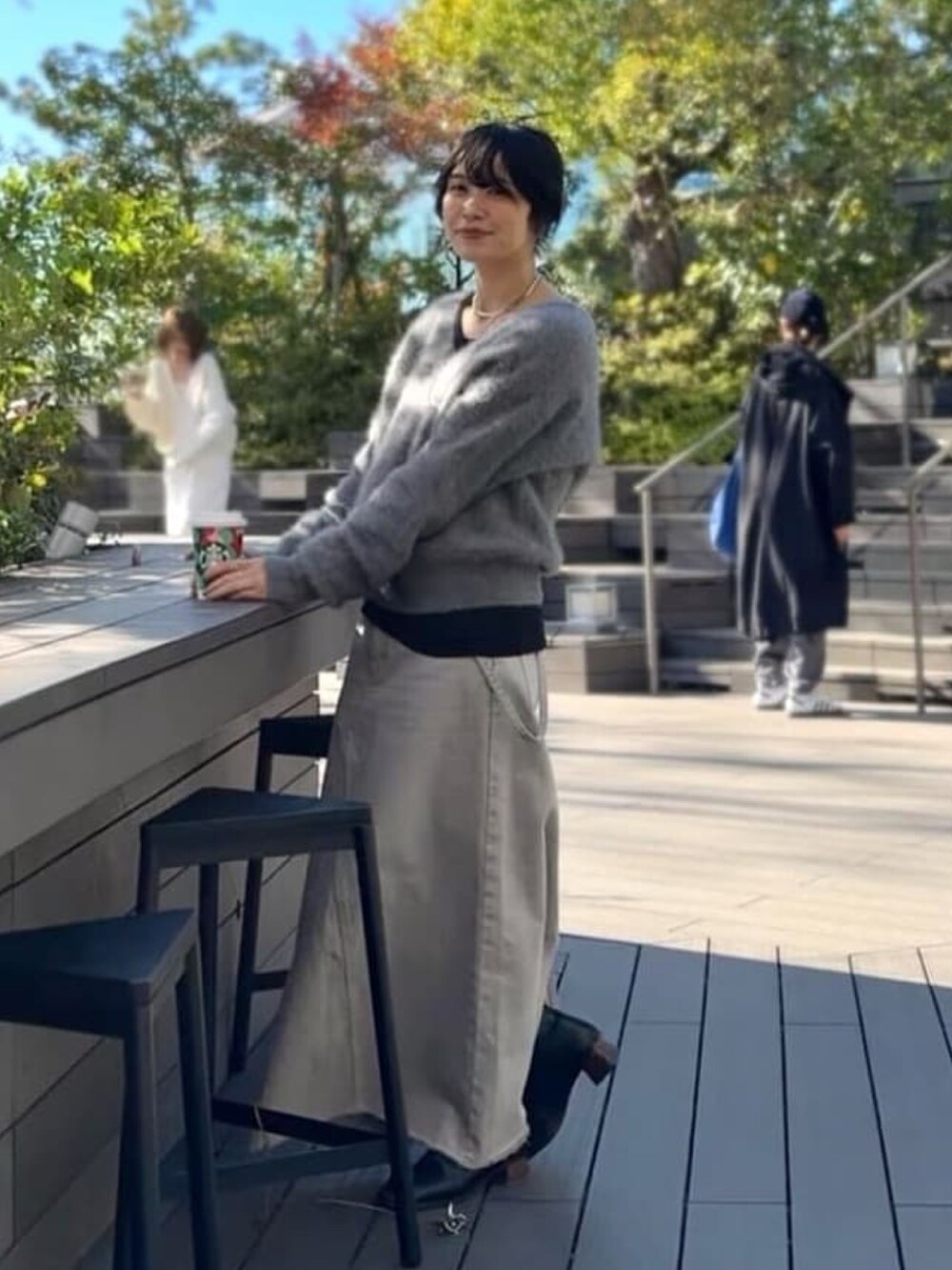 グレー系のニット/セーター、グレー系のデニムスカート、ブラック系のTシャツ/カットソーを着用したレディースの冬コーディネートの3枚目の写真