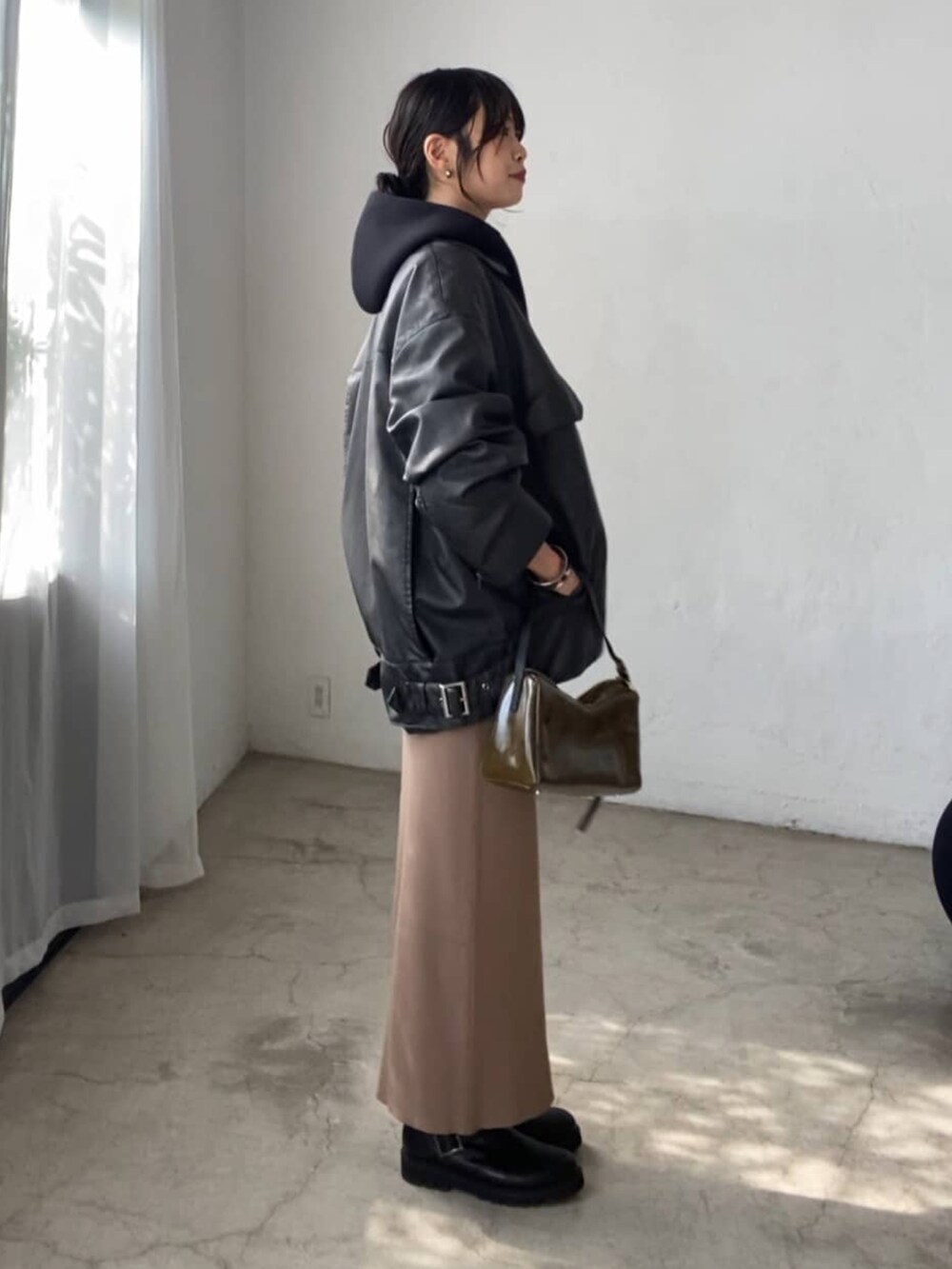 ブラック系のブルゾン、ブラウン系のスカート、ブラック系のショルダーバッグを着用したレディースの夏コーディネートの2枚目の写真