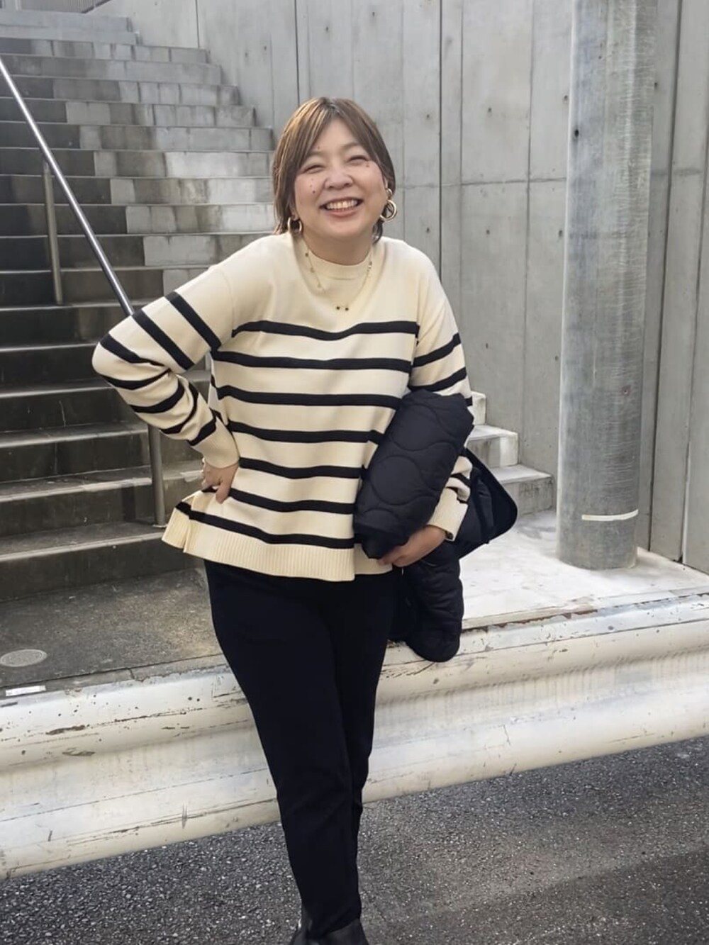 ブラック系のダウンジャケット/コート、ホワイト系のニット/セーター、ブラック系のスウェットパンツを着用したレディースの秋コーディネートの2枚目の写真