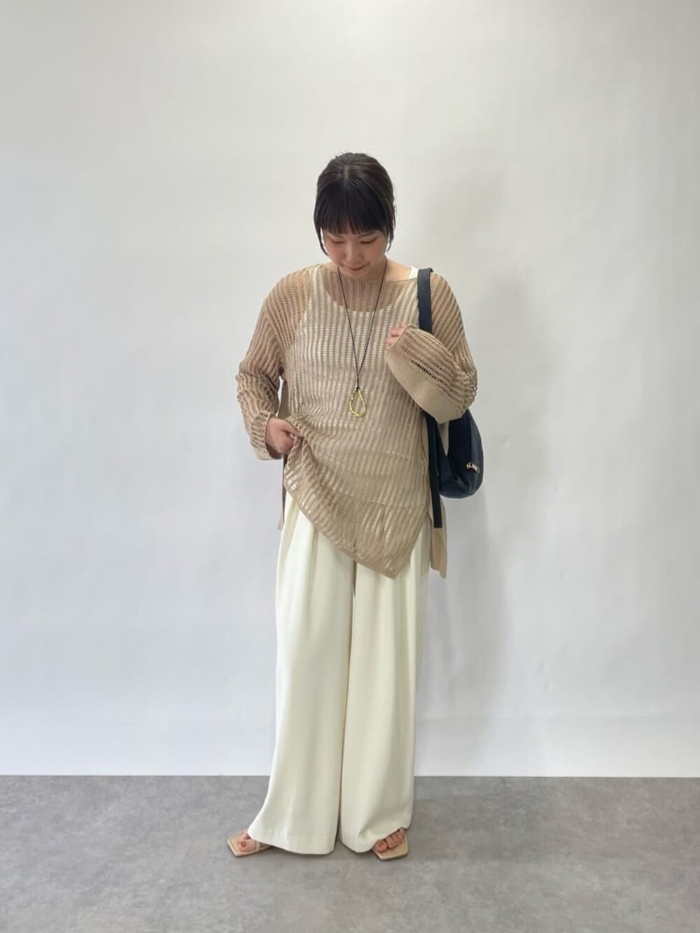 ホワイト系のニット/セーター、ホワイト系のスラックス、ブルー系のサンダルを着用したレディースの春コーディネートの4枚目の写真