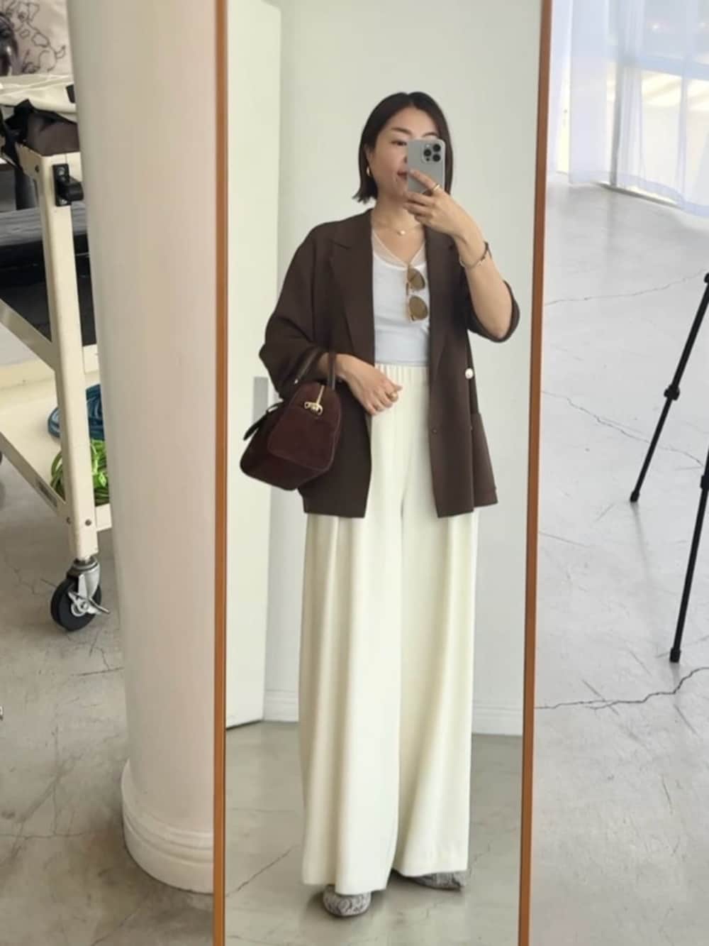 ホワイト系のスラックス、グレー系のパンプス、ホワイト系のキャミソールを着用したレディースの夏コーディネートの5枚目の写真