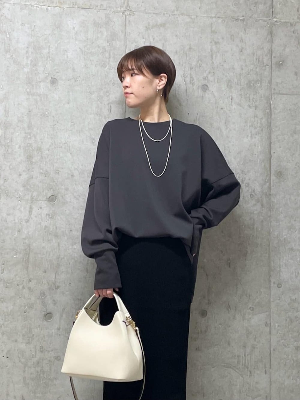 グレー系のTシャツ/カットソー、ブラック系のスカート、ブラック系のブーツを着用したレディースの冬コーディネートの3枚目の写真