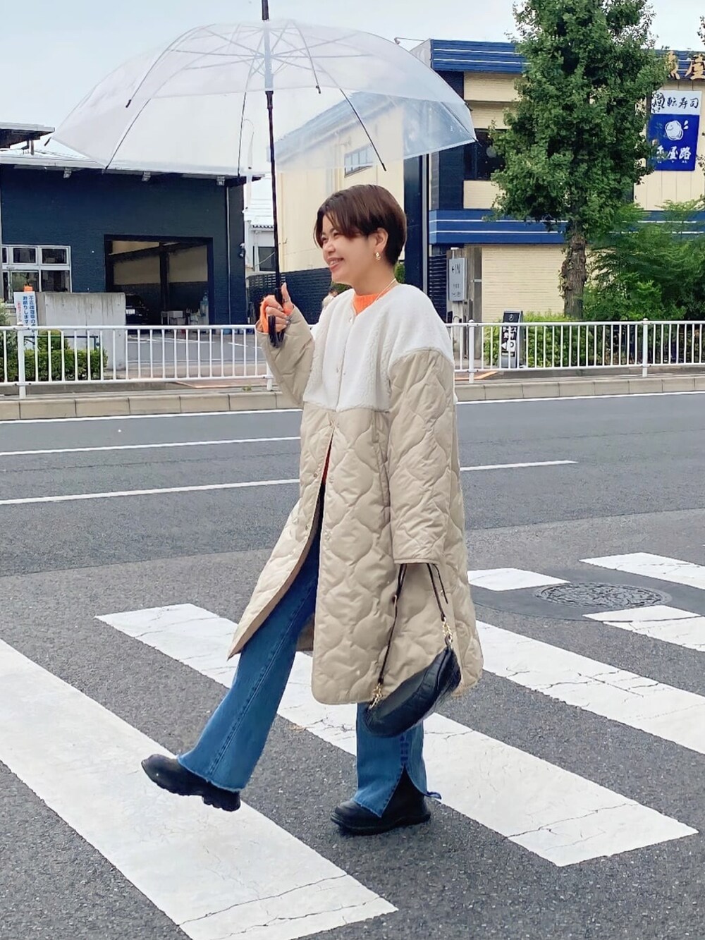 ブルー系のデニムパンツ、ベージュ系のダウンジャケット/コート、オレンジ系のニット/セーターを着用したレディースの秋コーディネートの3枚目の写真