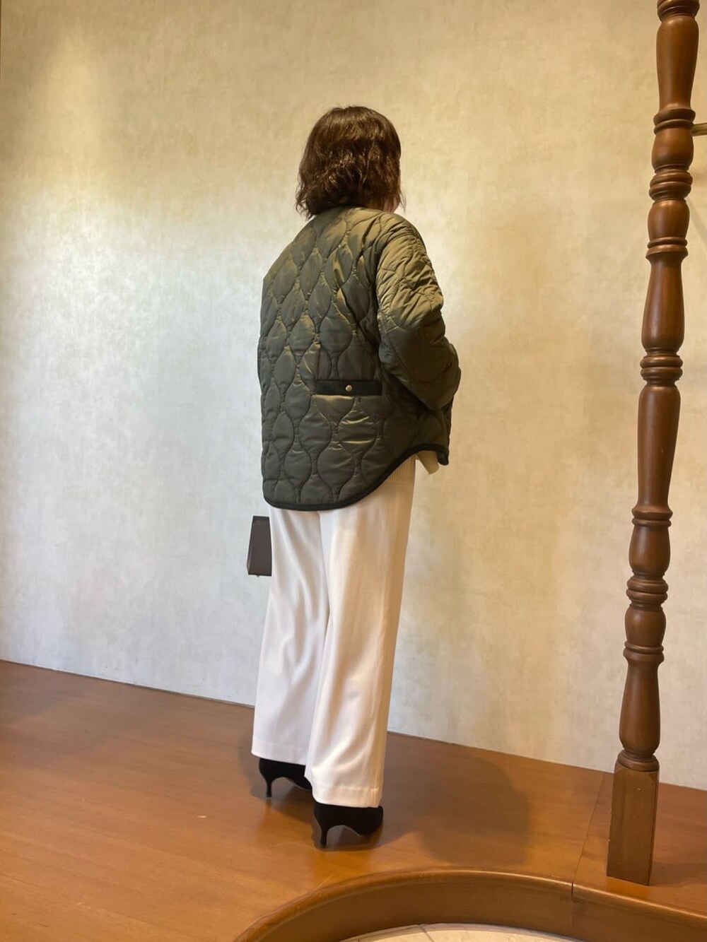 グリーン系のダウンジャケット/コート、ホワイト系のニット/セーター、ブラック系のブーツを着用したレディースの秋コーディネートの5枚目の写真