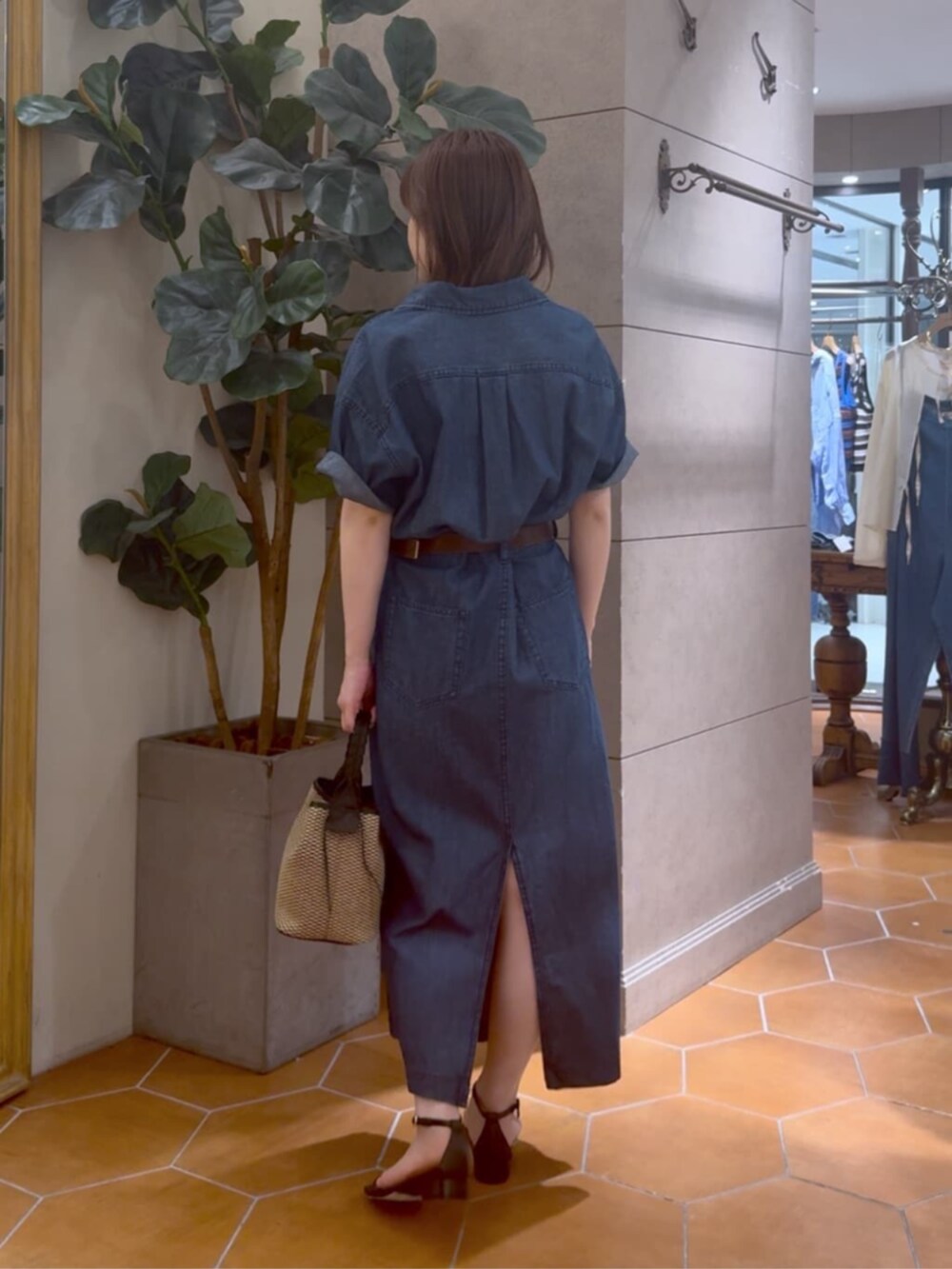 ブラック系のハンドバッグ、ブルー系のワンピース、ゴールド系のネックレスを着用したレディースの夏コーディネートの3枚目の写真