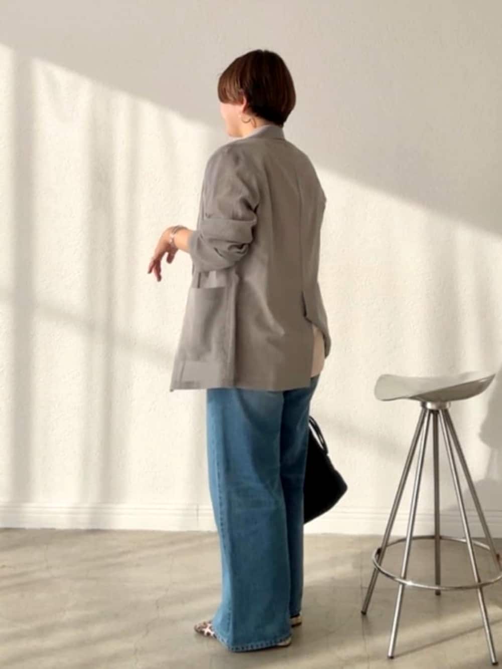 グレー系のテーラードジャケット、ブルー系のデニムパンツ、ベージュ系のその他シューズを着用したレディースの春コーディネートの2枚目の写真