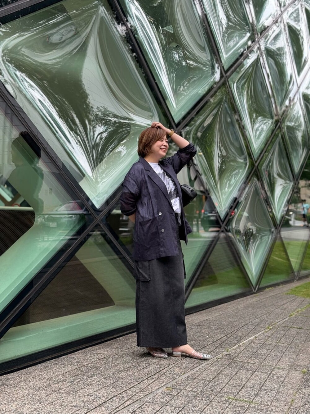 ブルー系のテーラードジャケット、ブルー系のデニムスカート、シルバー系のサンダルを着用したレディースの夏コーディネートの2枚目の写真