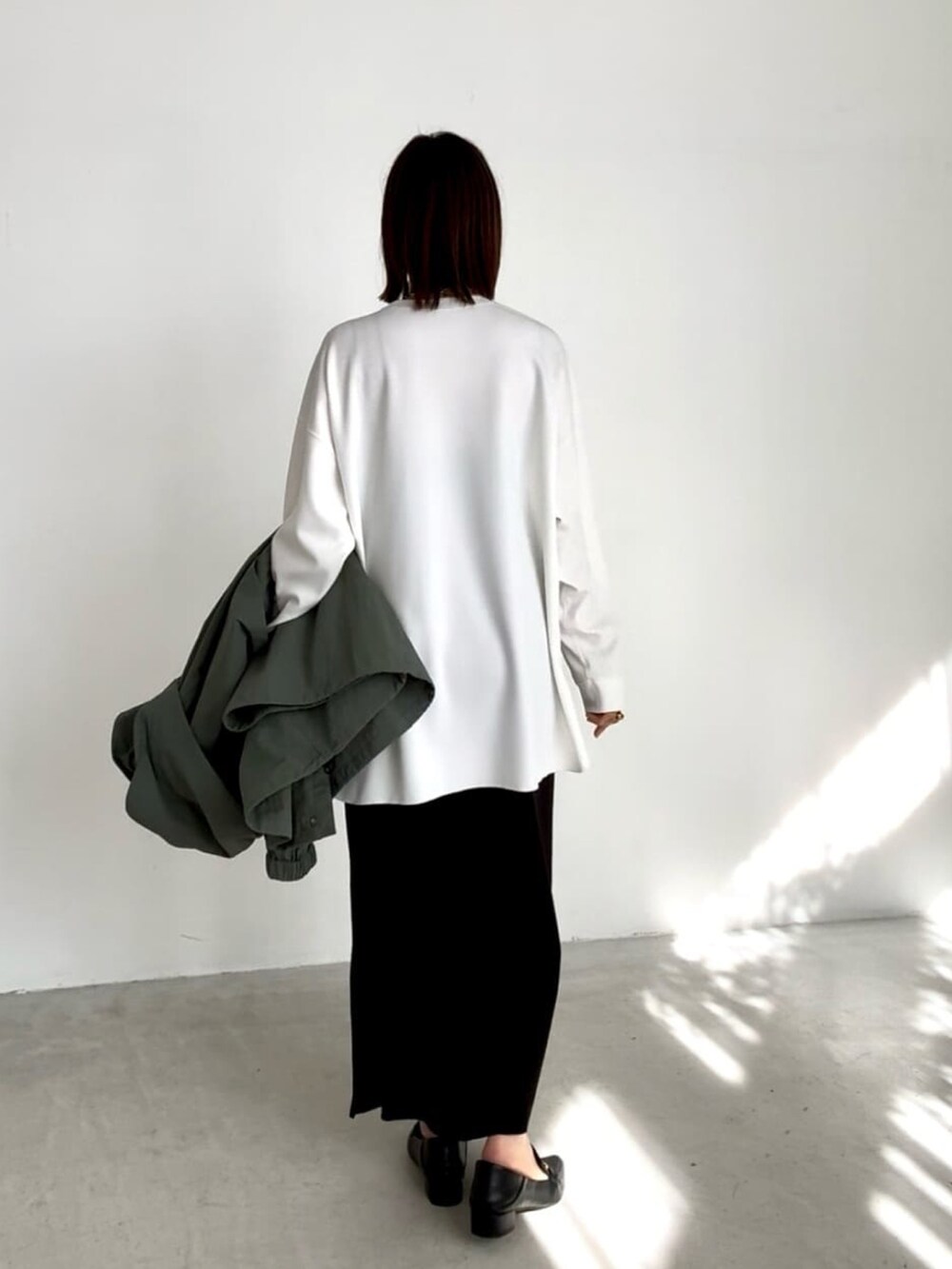 ホワイト系のTシャツ/カットソー、ブラック系のスカート、ブラック系のローファーを着用したレディースの冬コーディネートの2枚目の写真