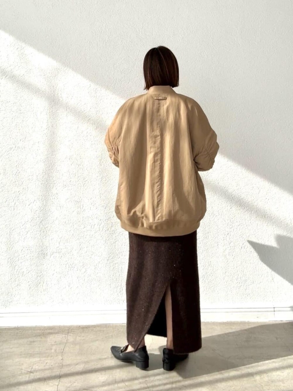 ブラウン系のスカート、ベージュ系のブルゾン、ホワイト系のTシャツ/カットソーを着用したレディースの秋コーディネートの4枚目の写真