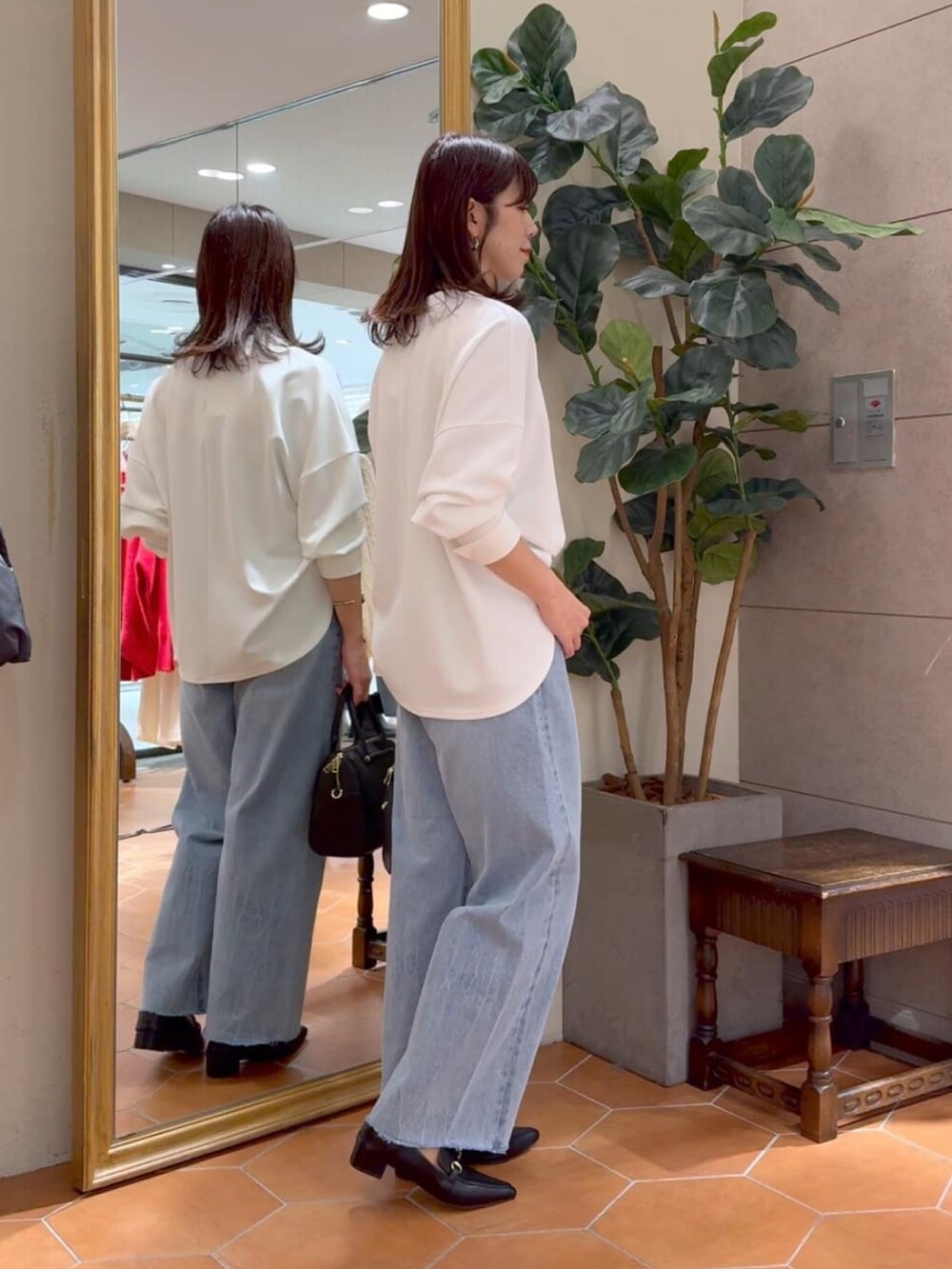 ホワイト系のTシャツ/カットソー、ブルー系のデニムパンツ、ブラック系のボストンバッグを着用したレディースの冬コーディネートの2枚目の写真