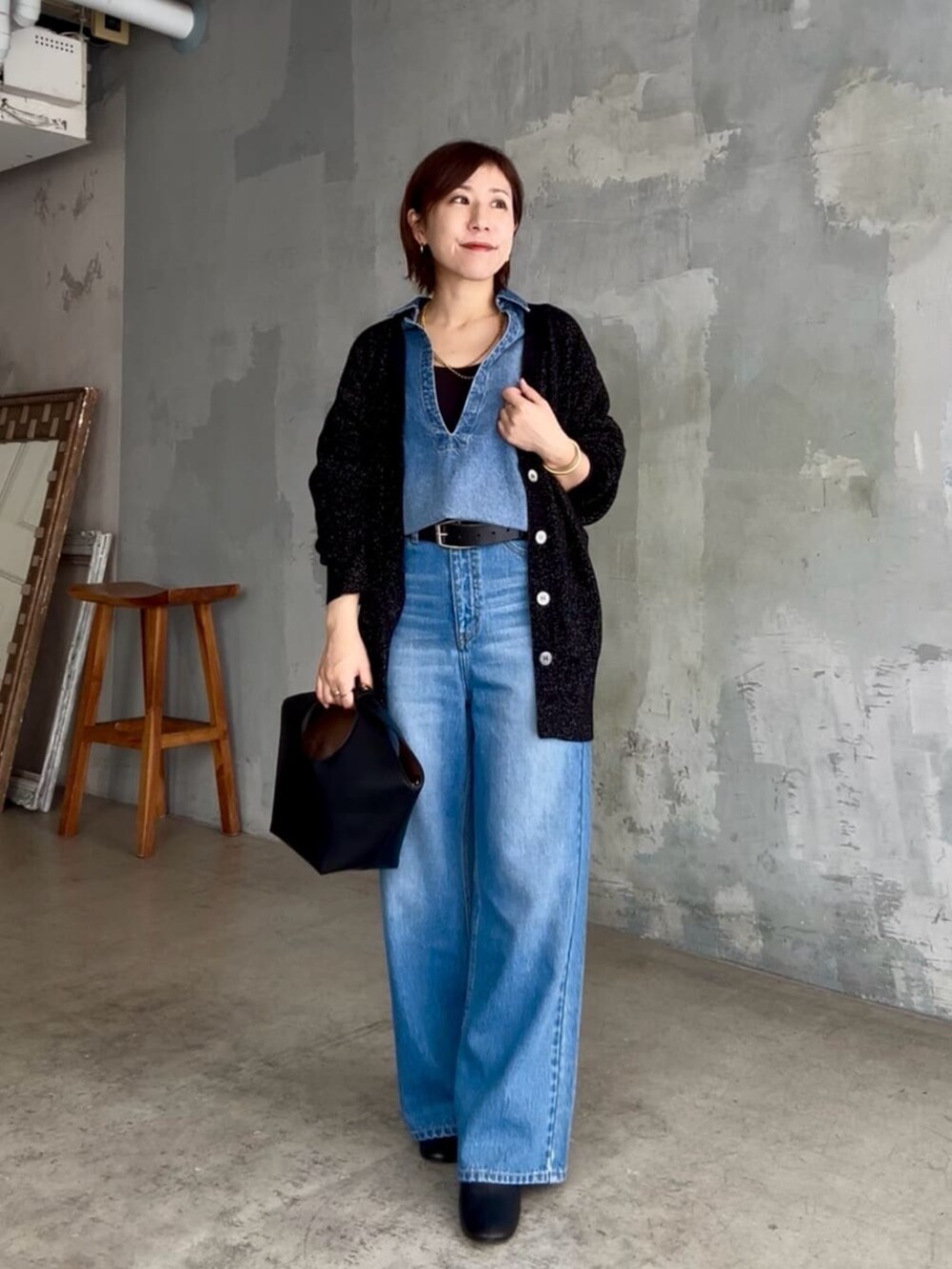 ブラック系のニット/セーター、ブルー系のシャツ/ブラウス、ブルー系のデニムパンツを着用したレディースの秋コーディネートの6枚目の写真
