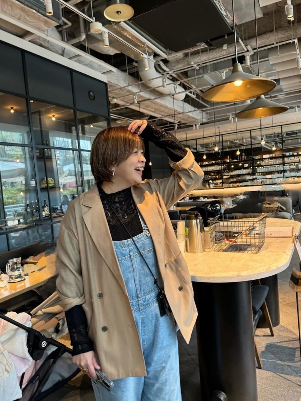 ブラック系のテーラードジャケット、ブルー系のサロペット/オーバーオール、ブラック系のTシャツ/カットソーを着用したレディースの春コーディネートの3枚目の写真