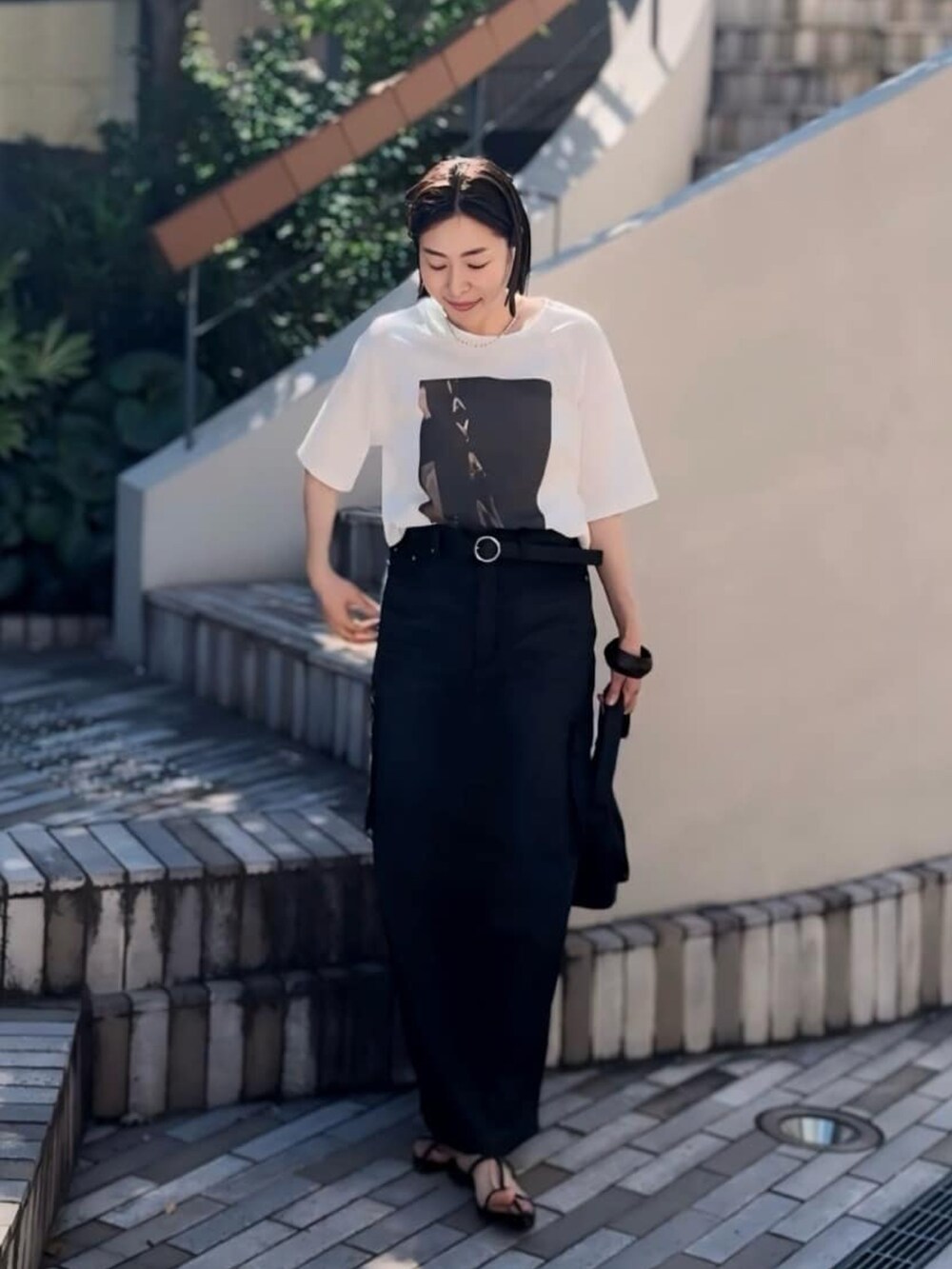 ブラウン系のTシャツ/カットソー、ブルー系のデニムスカート、ブラック系のボディバッグ/ウエストポーチを着用したレディースの夏コーディネートの2枚目の写真