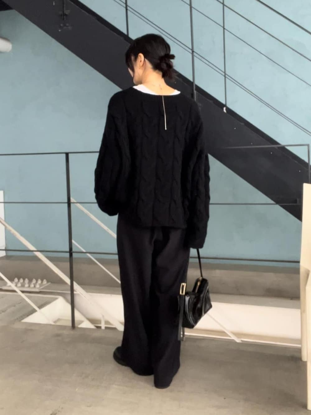 ブラック系のニット/セーター、ブラック系のスラックス、ブラック系のショルダーバッグを着用したレディースの秋コーディネートの3枚目の写真