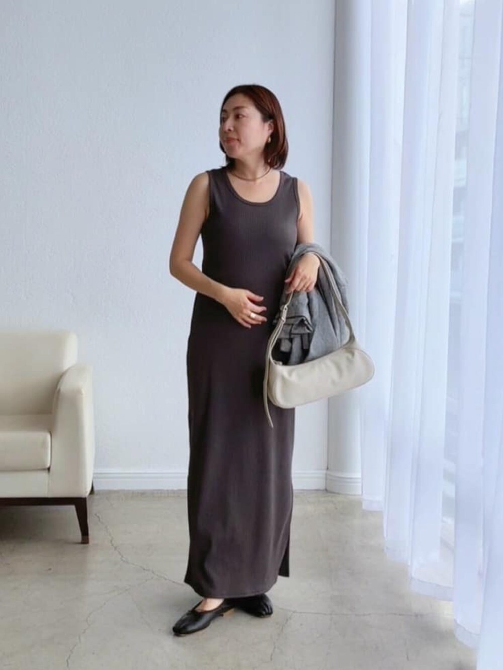 ブラック系のテーラードジャケット、ホワイト系のハンドバッグ、グレー系のワンピースを着用したレディースの冬コーディネートの4枚目の写真